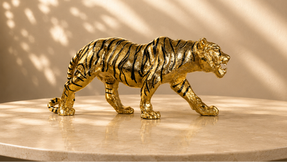 Gold tiger figurine on a reflective surface with a neutral background